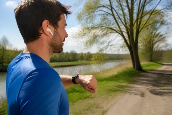 Homme consultant application running sur montre durant course en plein air près d'un lac