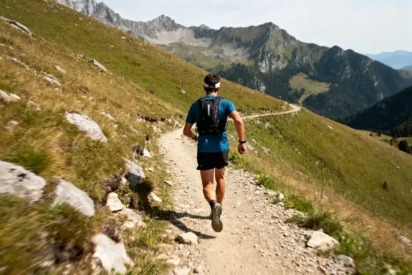 Homme courant sur sentier de montagne, parfait pour entraînement pour le trail en plein air