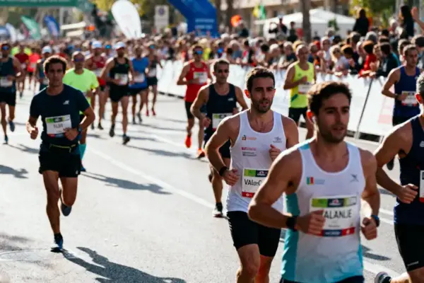 Un groupe de coureurs participe à un marathon, sur une route bordée de spectateurs et de bannières.