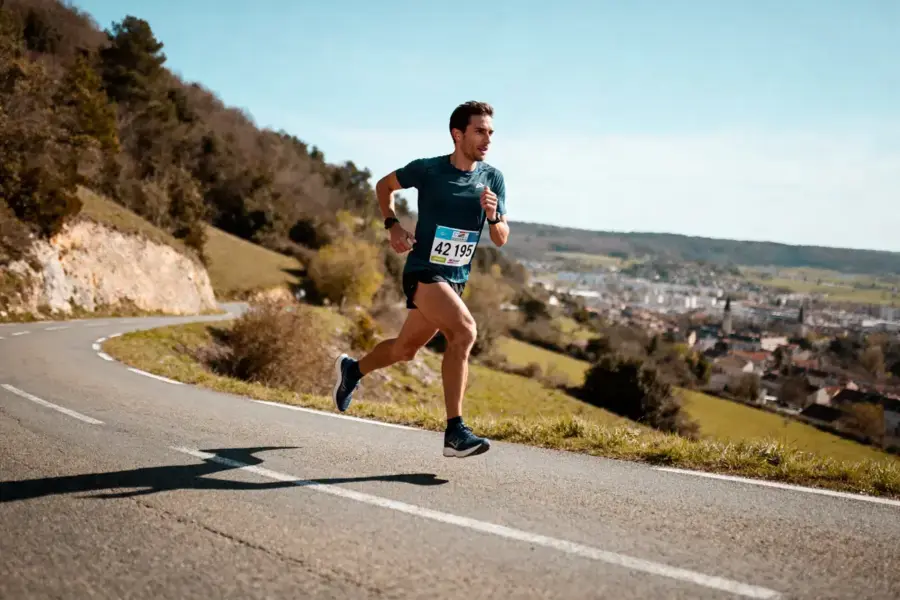 Coureur participant Ă une course de marathon sur route sinueuse avec vue panoramique