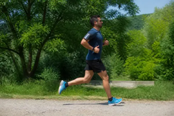 Homme courant avec écouteurs dans un parc, écoutant de la musique pour courir