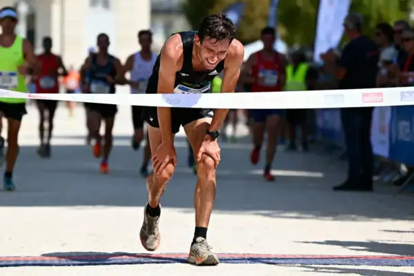 Un coureur franchissant la ligne d'arrivée d'une course, entouré par d'autres concurrents.